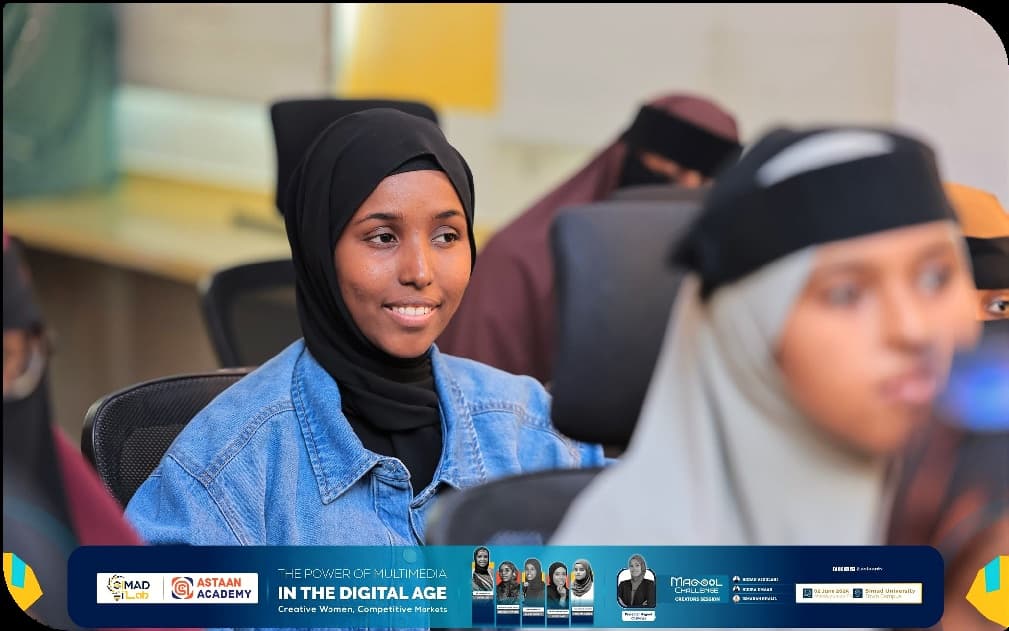 A smiling participant in a denim jacket during the multimedia workshop