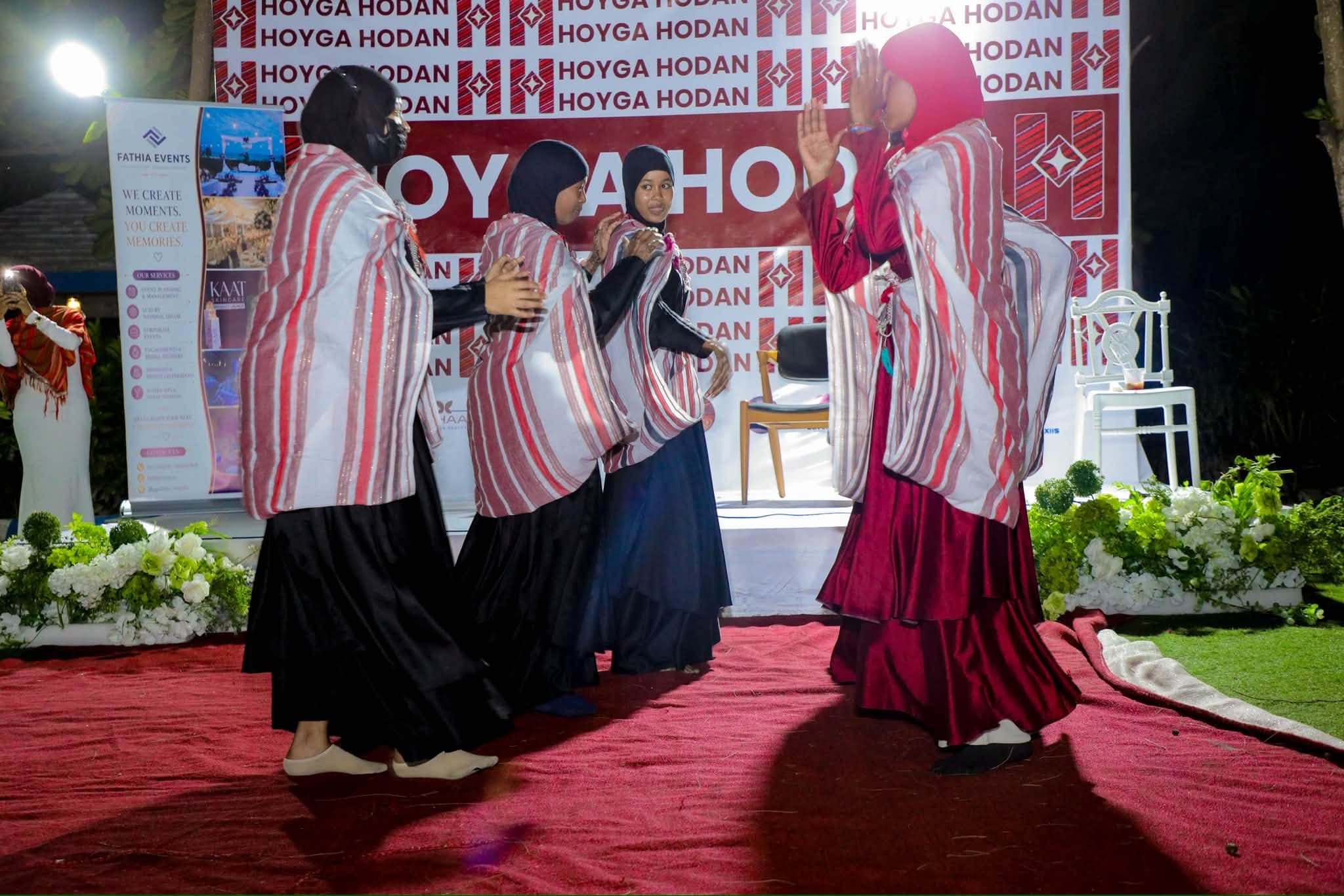 Dancers in striped traditional shawls perform on a red carpet at Hoyga Hodan